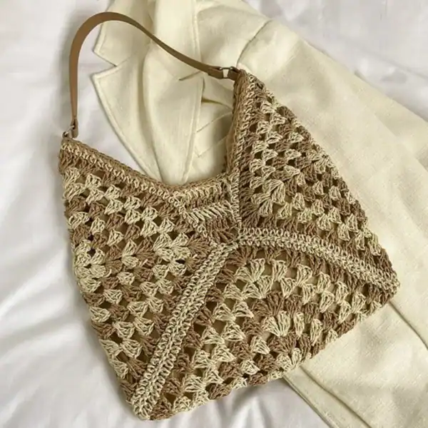 Virkad hobo väska i beige och naturtoner, handgjord med detaljerad stickmönster.