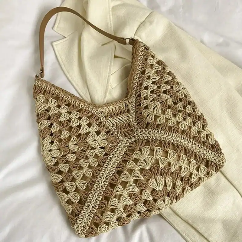 Virkad hobo väska i beige och naturtoner, handgjord med detaljerad stickmönster.