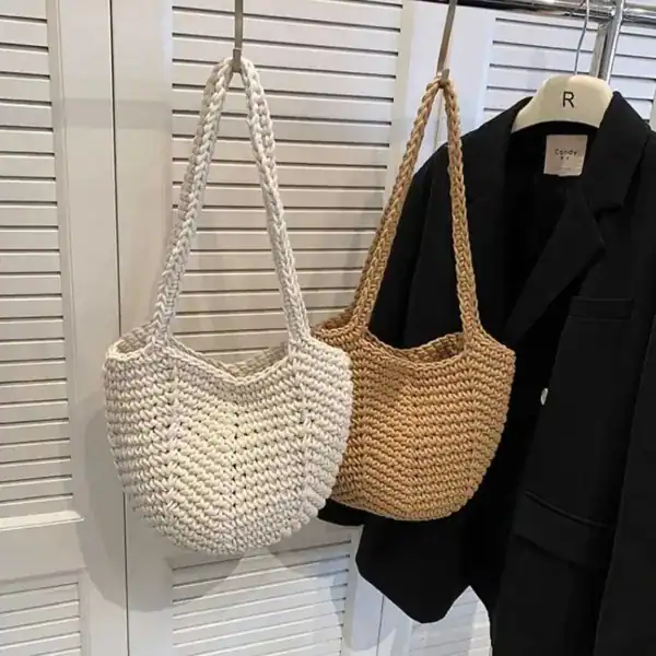 Virkad korgväska i vit och beige, hängande vid garderob.