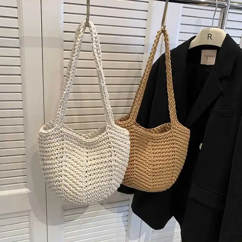 Virkad korgväska i vit och beige, hängande vid garderob.