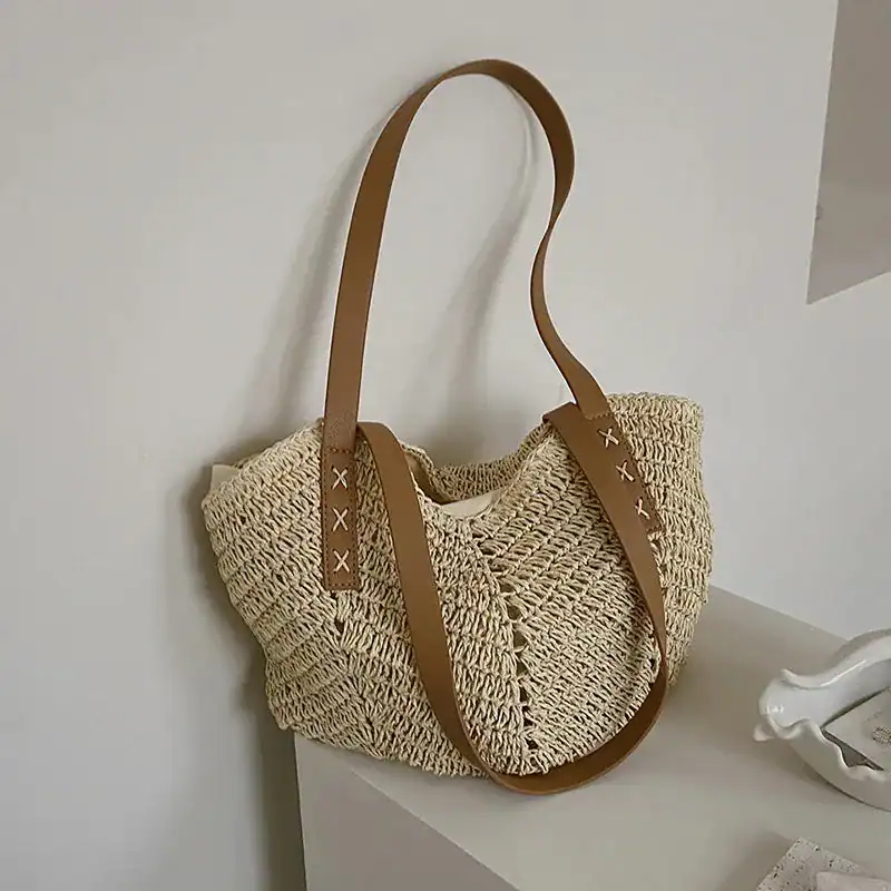 Virkad shoppingväska i naturfärgad rör, med bruna läderhandtag och X-formade snöre.