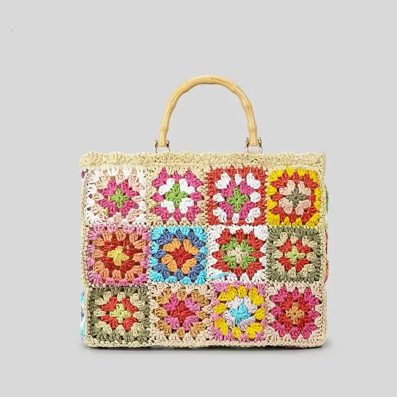 Virkad strandväska med färgglada granny square mönster och bambuhandtag.