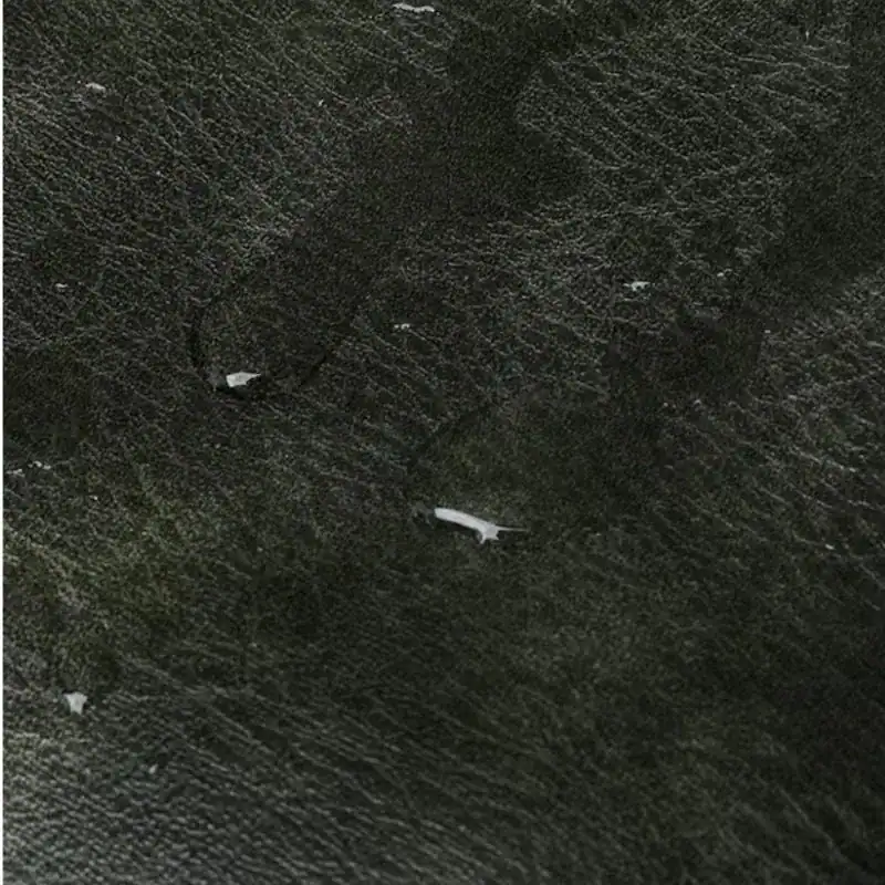 Vit bröstväska i mörk textil, detalj på tygtextur och sömn.