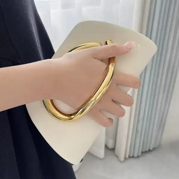 Vit clutch med guldhandtag, elegant handväska för kvällsklänning.