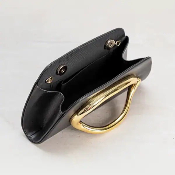 Svart clutch med guldhandtag och inre fack, elegant axelväska för kvinnor.