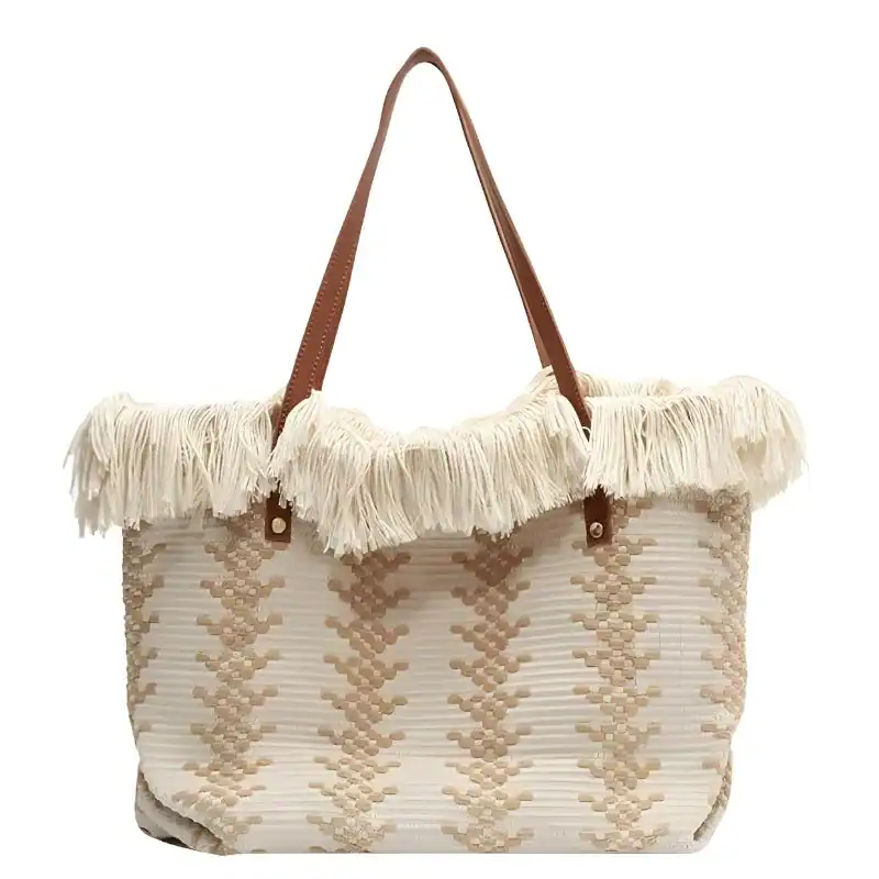 Vit fransad strandkorg med beige mönster och bruna handtag.
