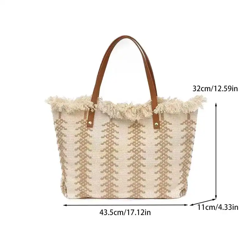 Vit fransad strandkorg med beige mönster och bruna handtag.