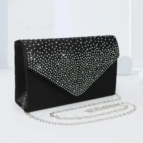 Svart glitterclutch med pärlor och kedja, perfekt för festliga tillfällen.