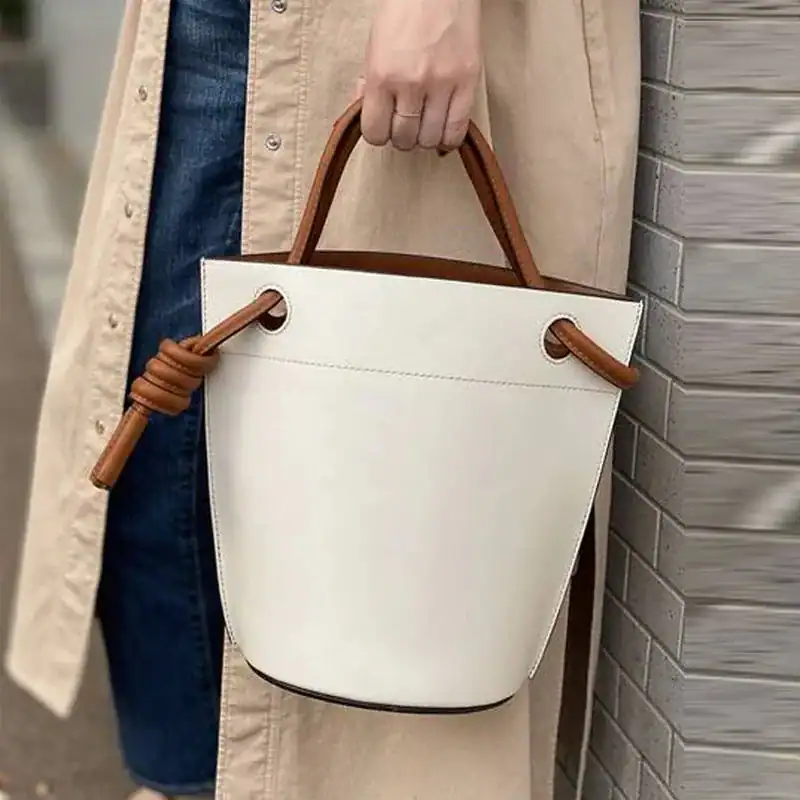 Vit hinkväska med bruna handtag och knutdetalj, modeaccessoarer för kvinnor.