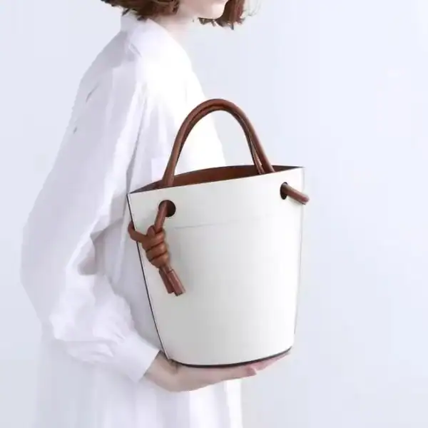Vit hinkväska med bruna handtag och knutdetalj, modeaccessoarer för kvinnor.