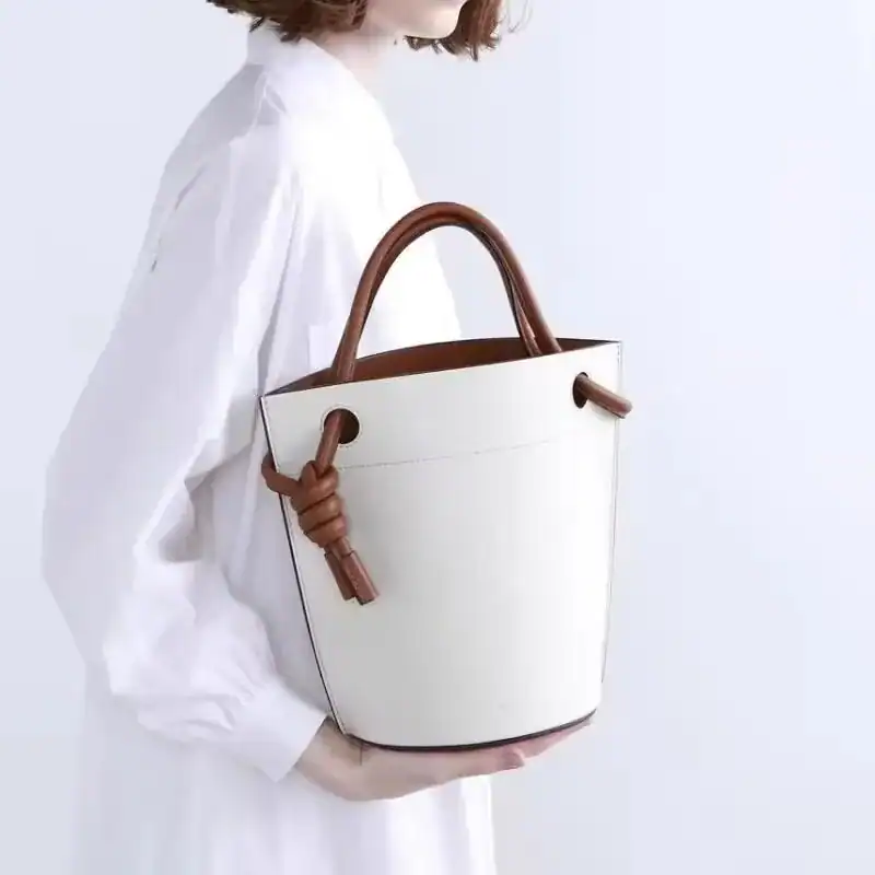 Vit hinkväska med bruna handtag och knutdetalj, modeaccessoarer för kvinnor.