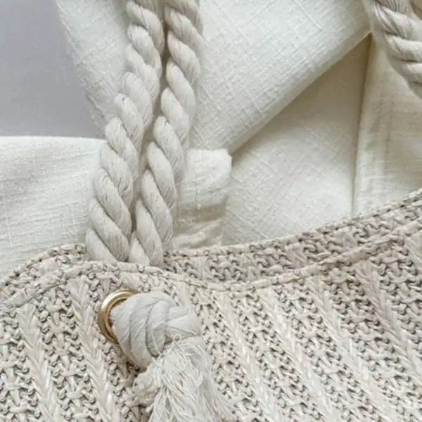 Vit korgväska med repband och tass, textil och naturmaterial.