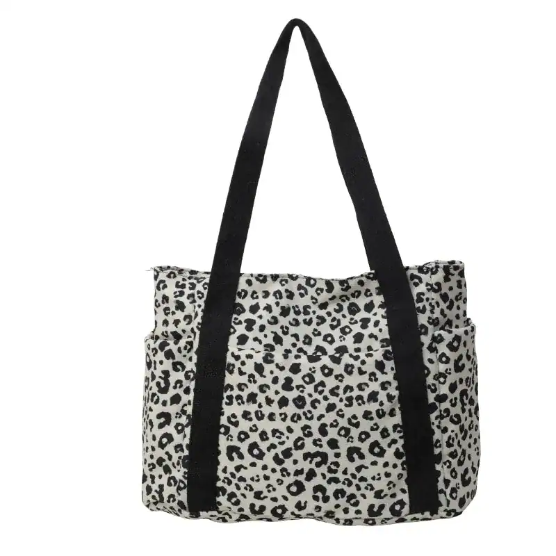 Vit leopard mönstrad axelväska med svarta handtag.