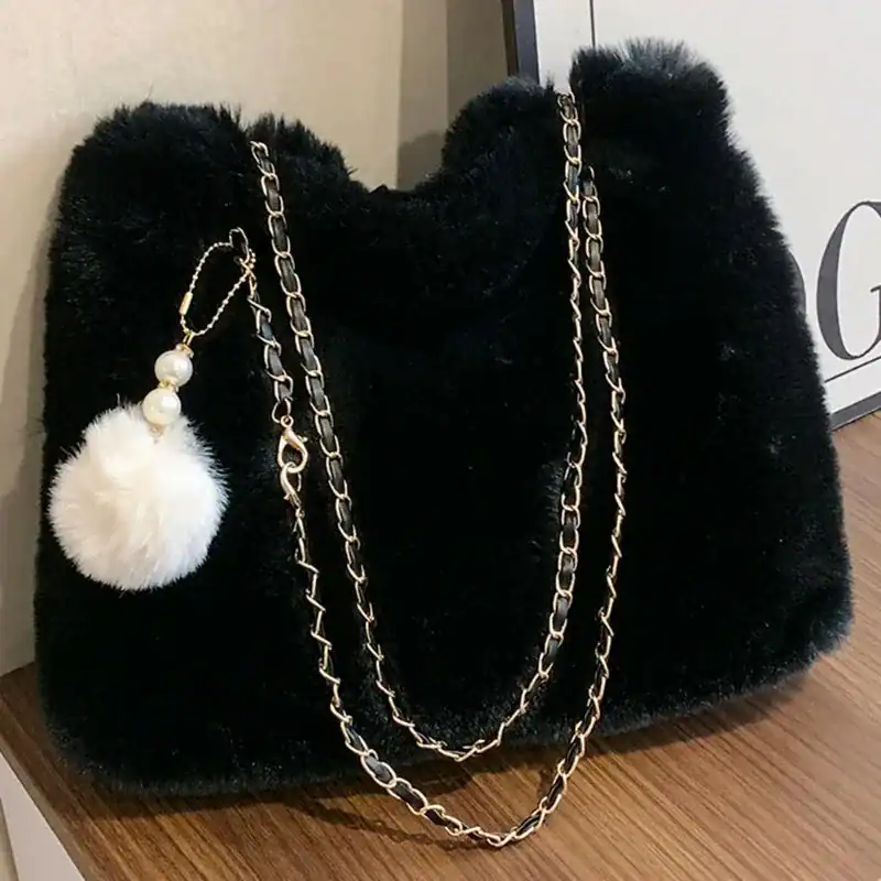 Svart päls axelväska med guld kedja och vit pompom.