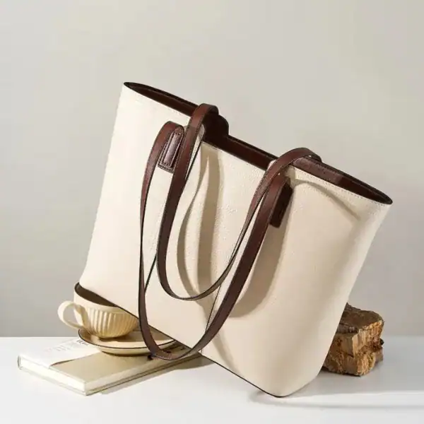 Vit shoppingväska med bruna läderhandtag, stilren och praktisk för daglig användning.